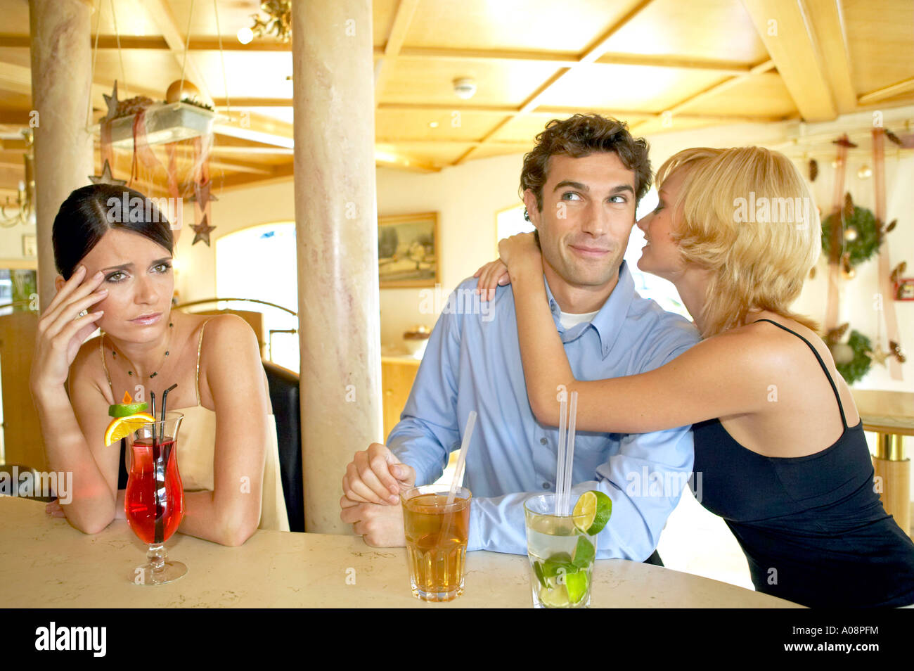Mann flirtet mit zwei Frauen an der Hotelbar Eifersucht, Man flirting with two women at a hotel bar jealousy Stock Photo
