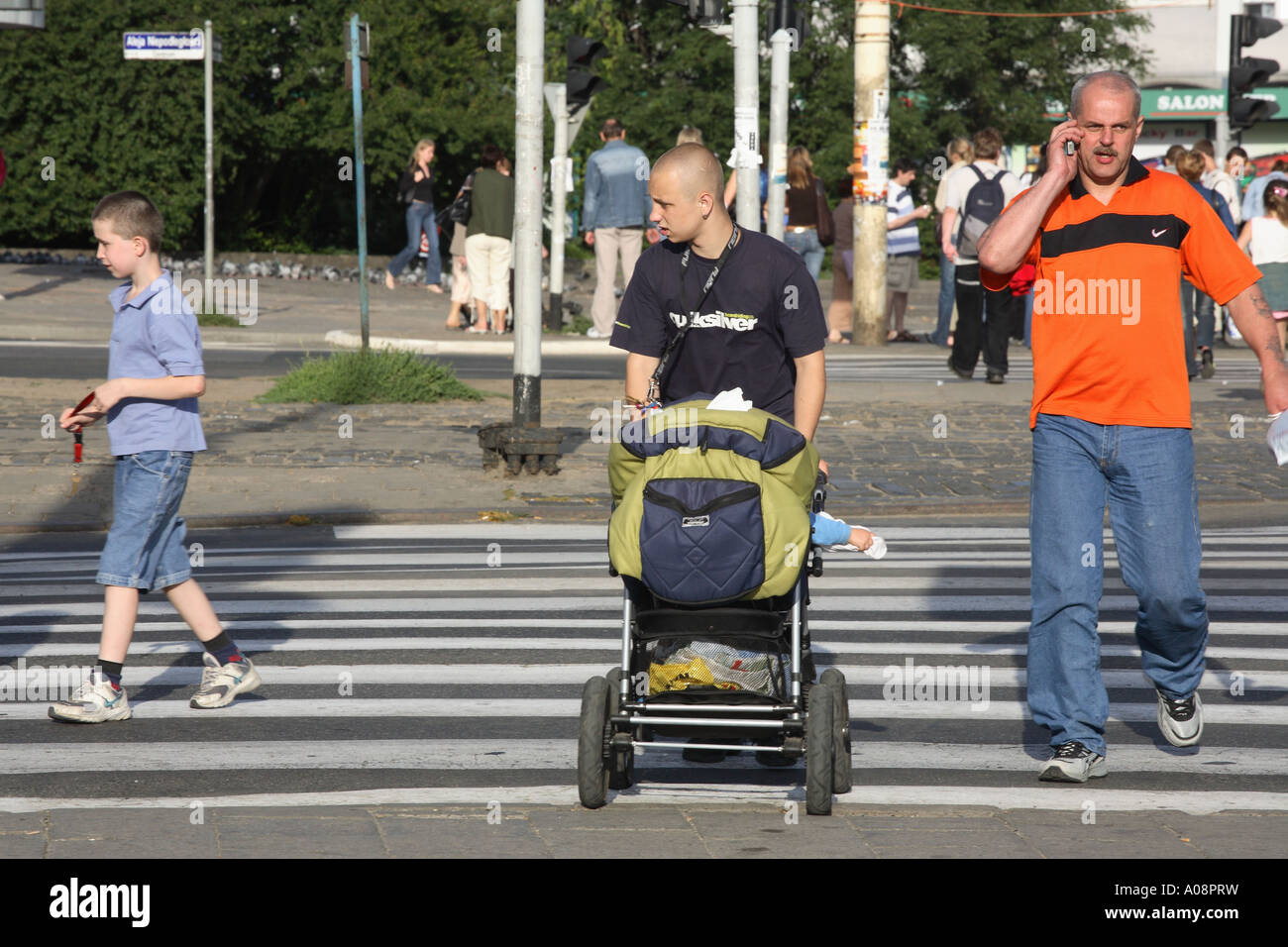 Pedestrians crossing a street in Sczeczin, Poland. A young man is pushing a pram Stock Photo