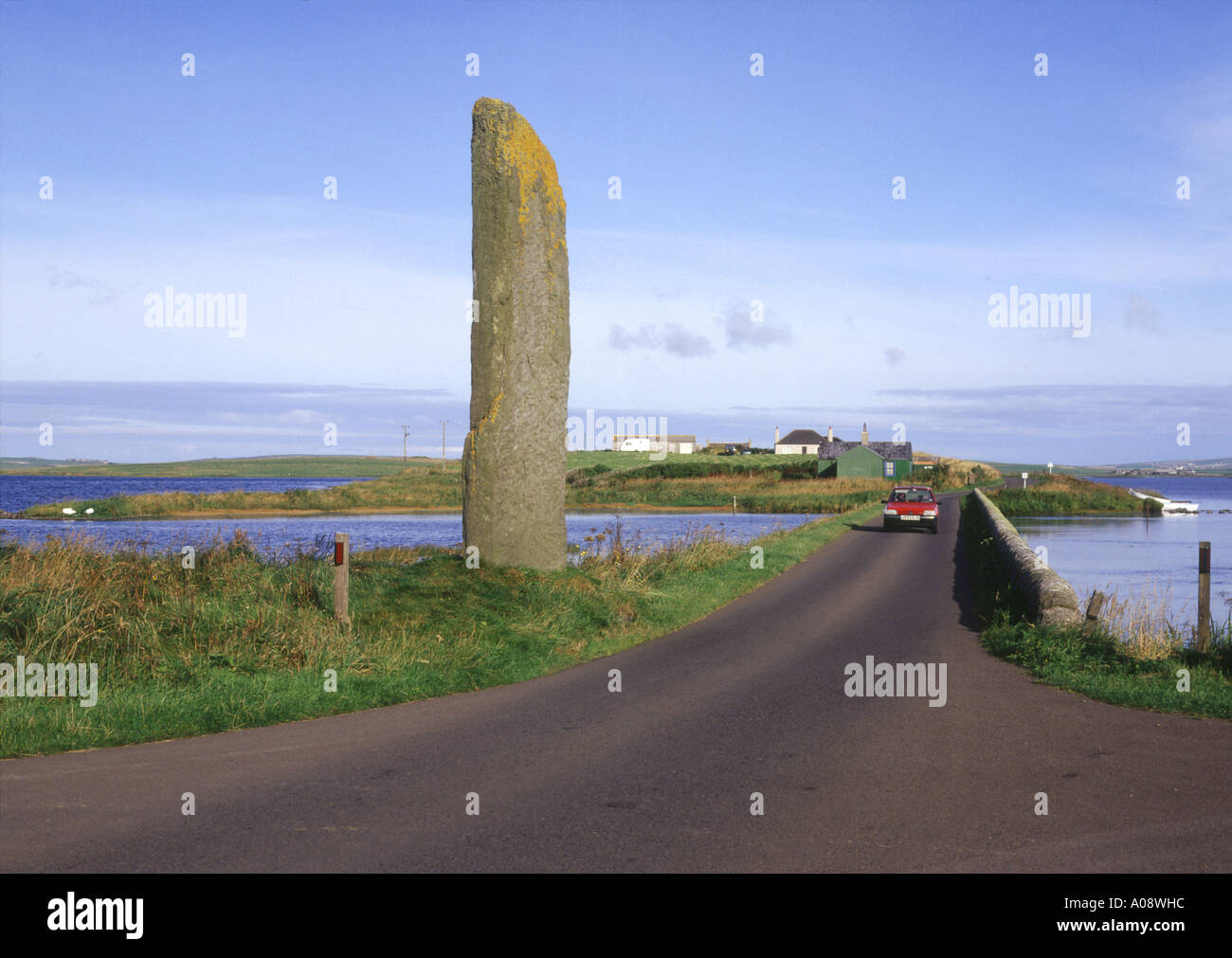 dh Watch stone STENNESS ORKNEY Standing stone car on road between Loch of Harray and Loch of Stenness travel driving scotland Stock Photo