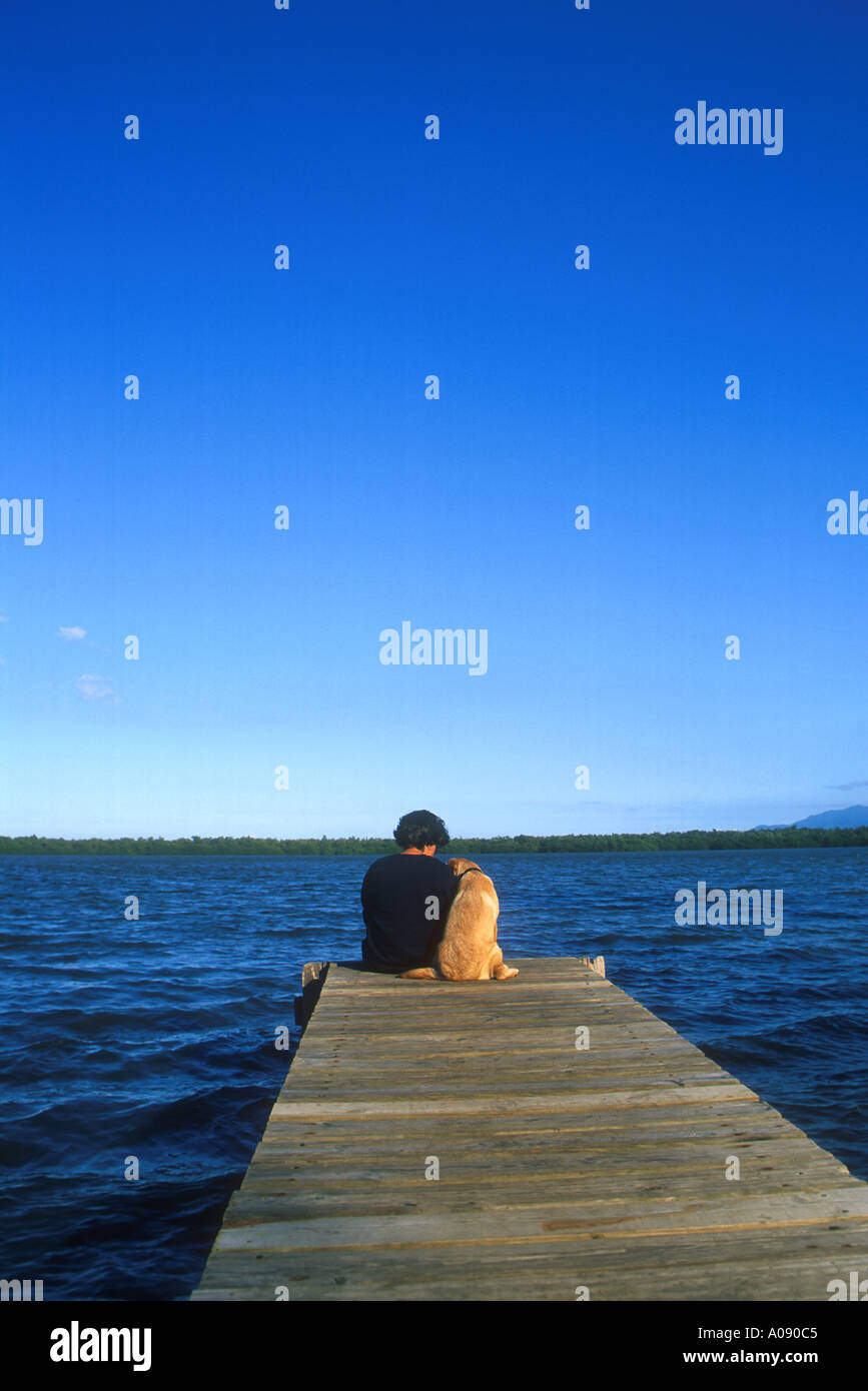 Woman and her puppy sitting on dock Stock Photo