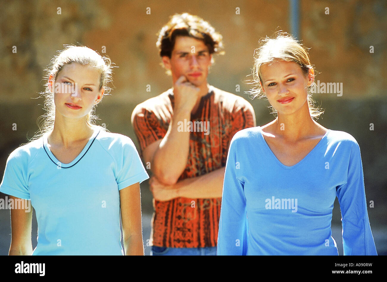 Two young women smiling with a young man standing behind Stock Photo ...