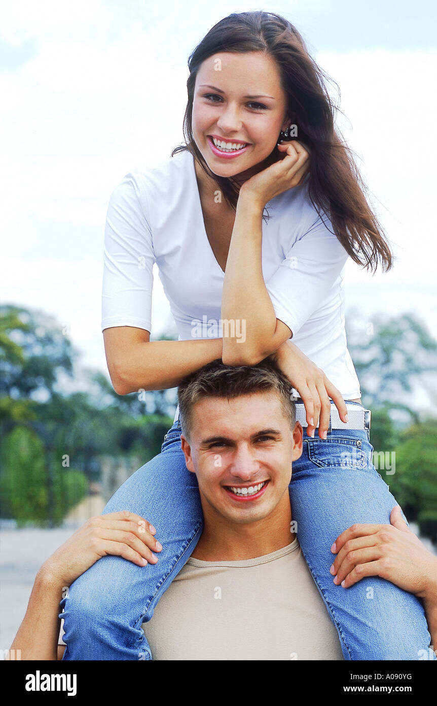 Portrait of a young woman sitting on a young mans shoulders Stock Photo