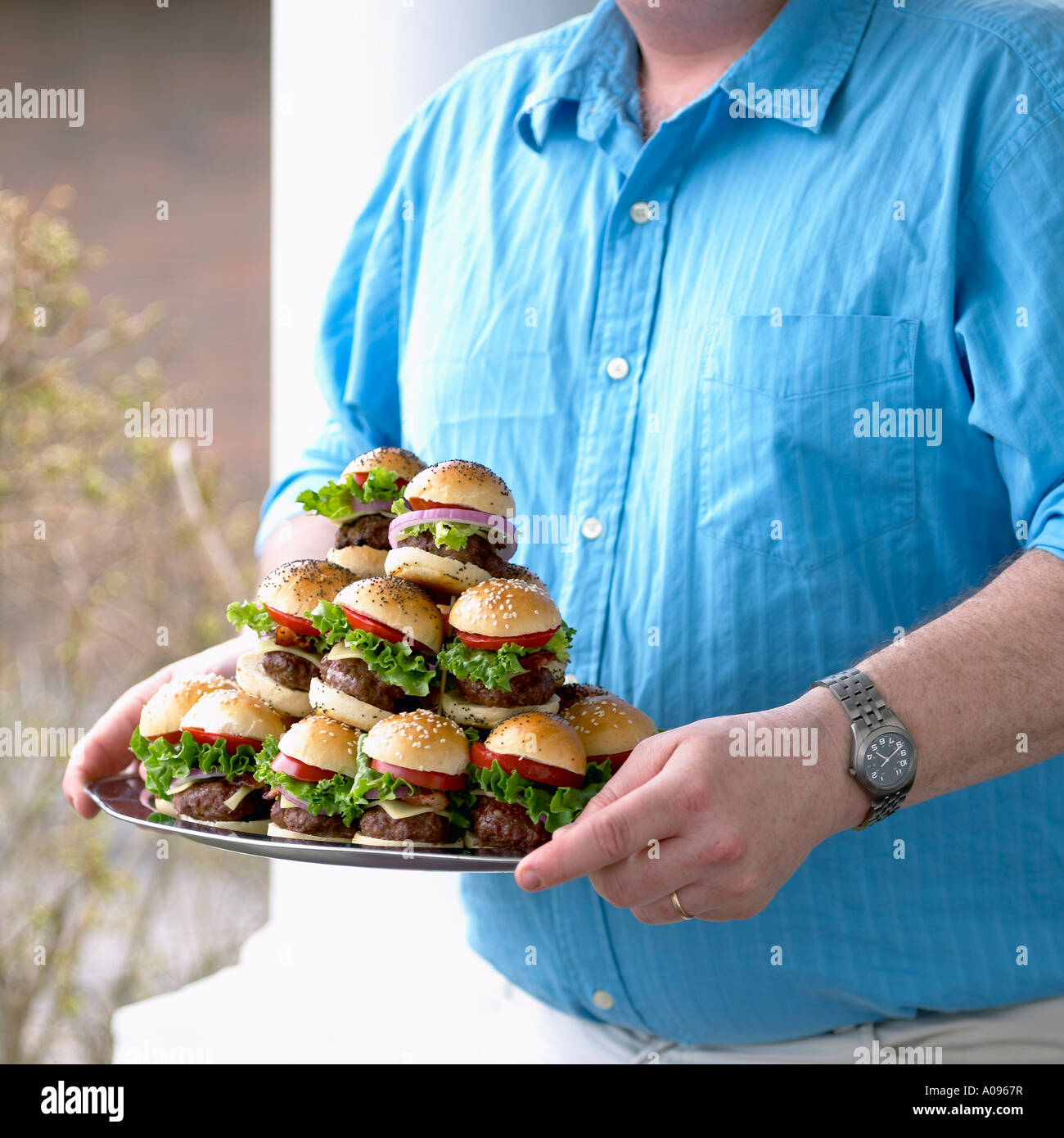 Man Carrying Plate of Small Hamburgers Stock Photo