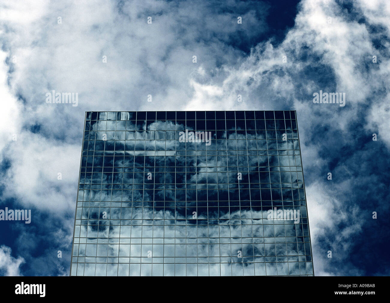 The top section of a skyscraper with white clouds reflecting in its ...