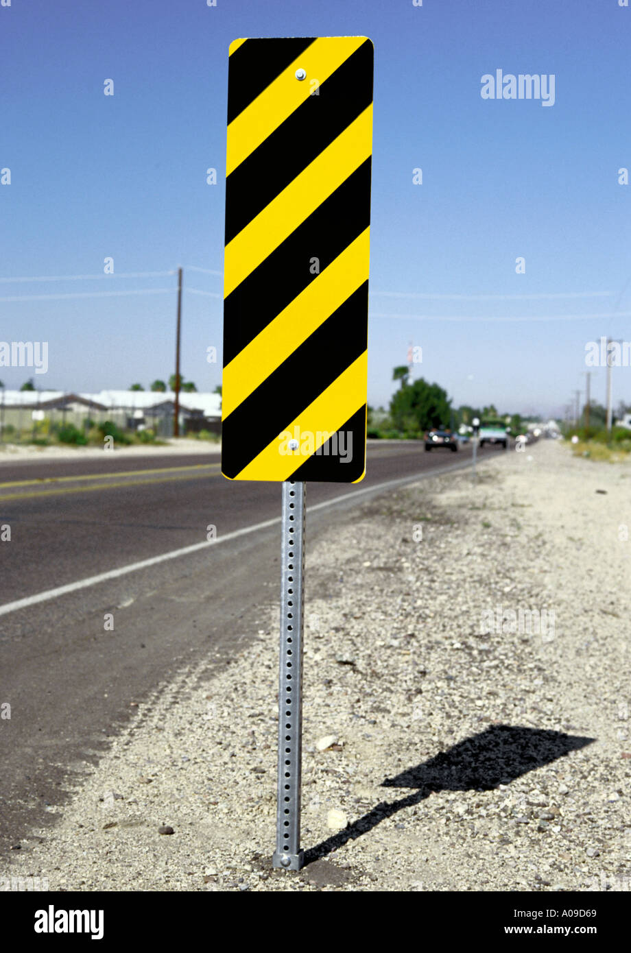 yellow-and-black-diagonally-striped-rectangular-hazard-beside-road-sign