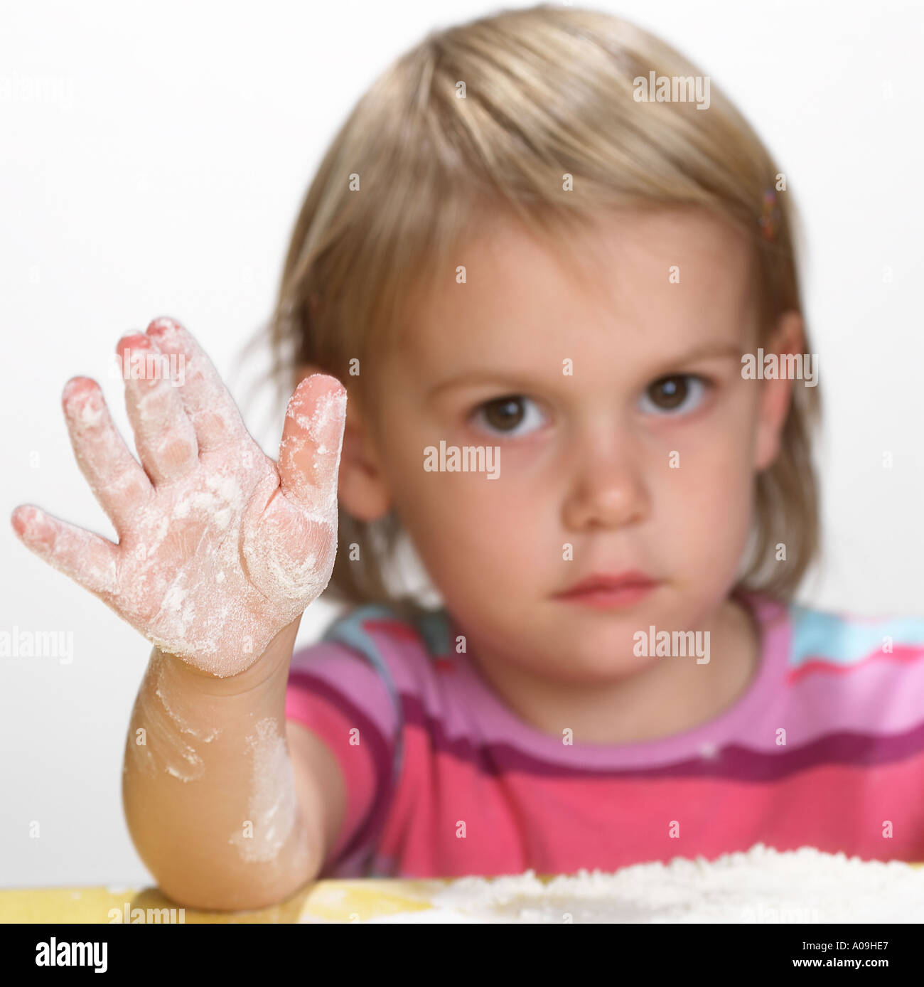 Little girl cooking holding up a hand covered in flour Keywords child
