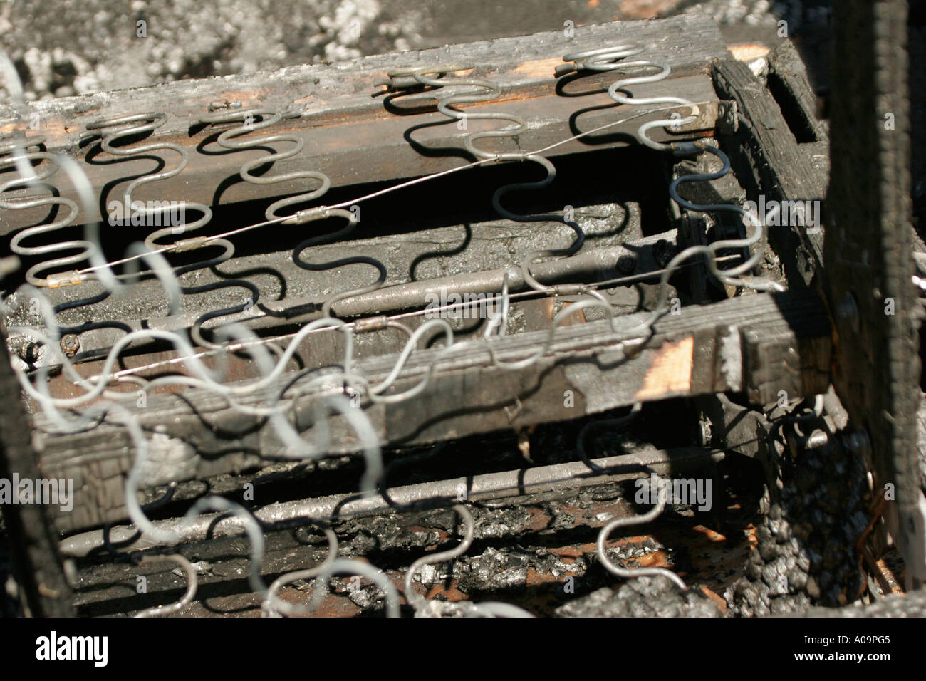 The wood charcoal ash remains of a lounge chair in a fire burnt structure Stock Photo