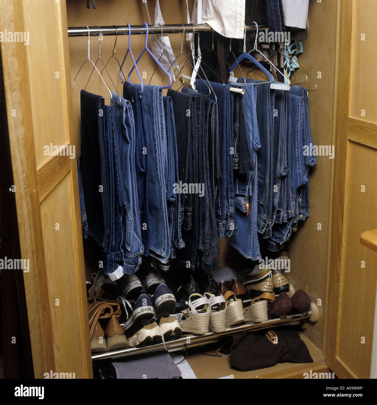 a selection of jeans and shoes hanging in a wardrobe Stock Photo