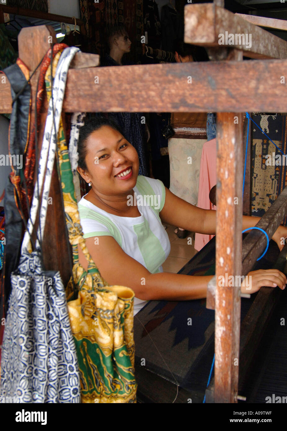 Balinese dress maker working at hand powered silk weaving loom, Ubud, Bali Indonesia Stock Photo
