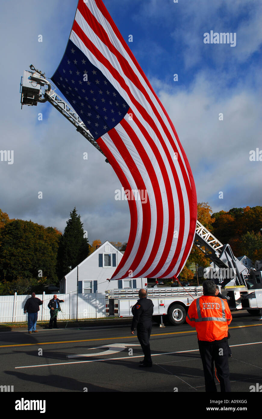 Firefighters set up a massive flag before a funeral procession for a fallen police officer Stock Photo