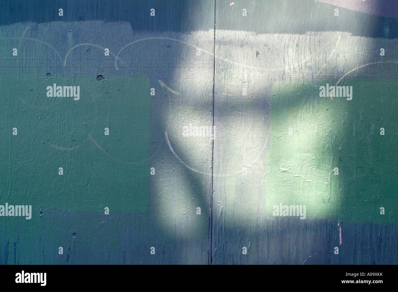 Light on a painted wooden wall forms an abstract pattern background with hues of green Stock Photo