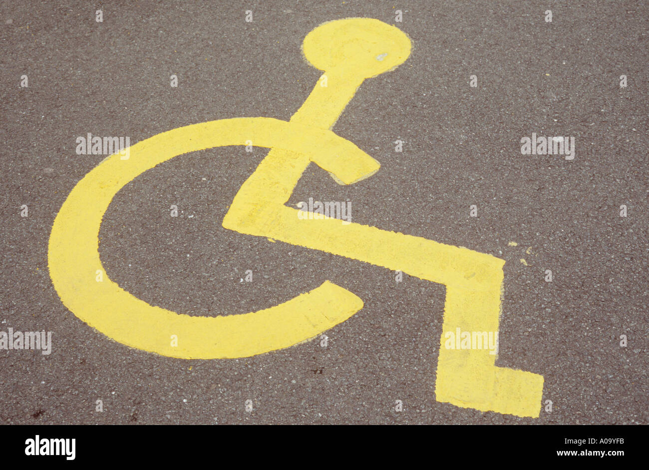 Symbol of person in wheelchair painted in yellow on road or carpark surface indicating Parking bay for disabled people only Stock Photo