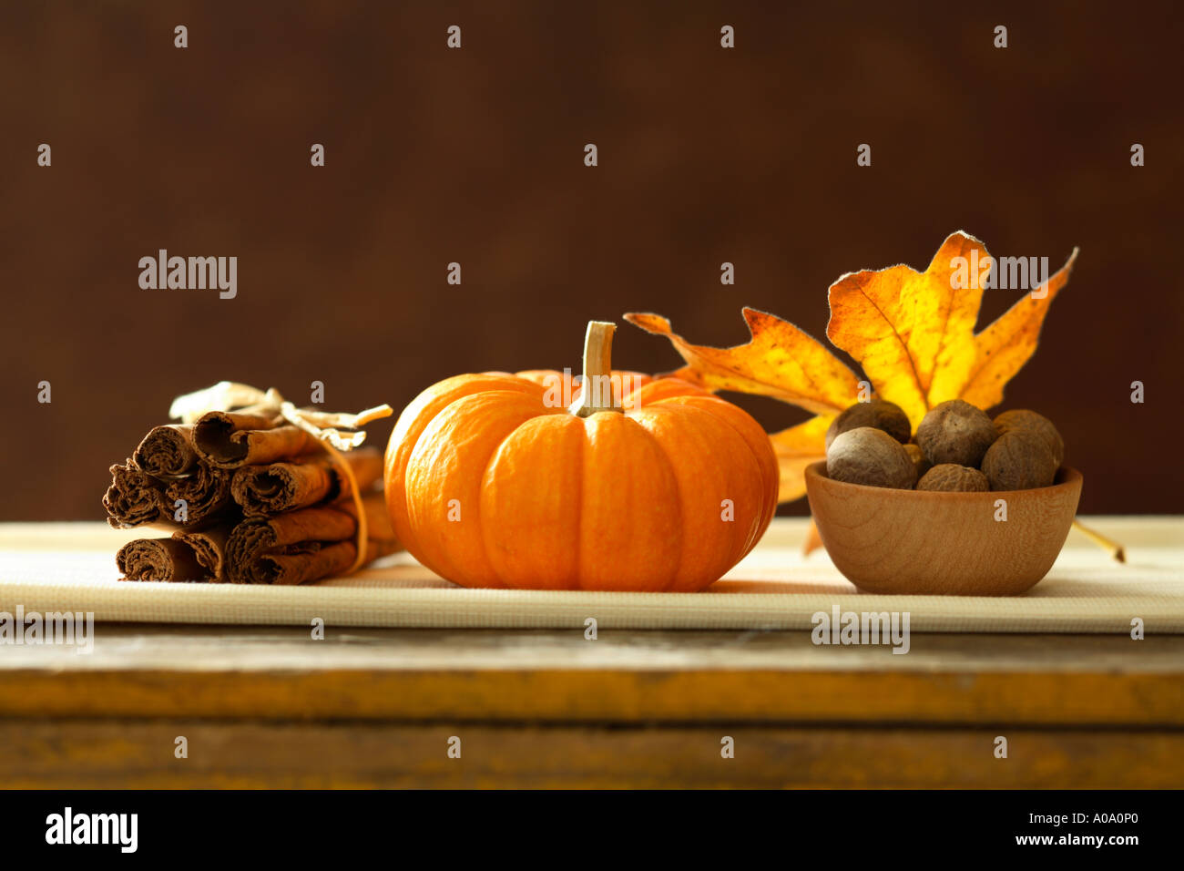 Autumn still life with pumpkin, cinnamon, nutmeg, spices and maple leaf. Stock Photo