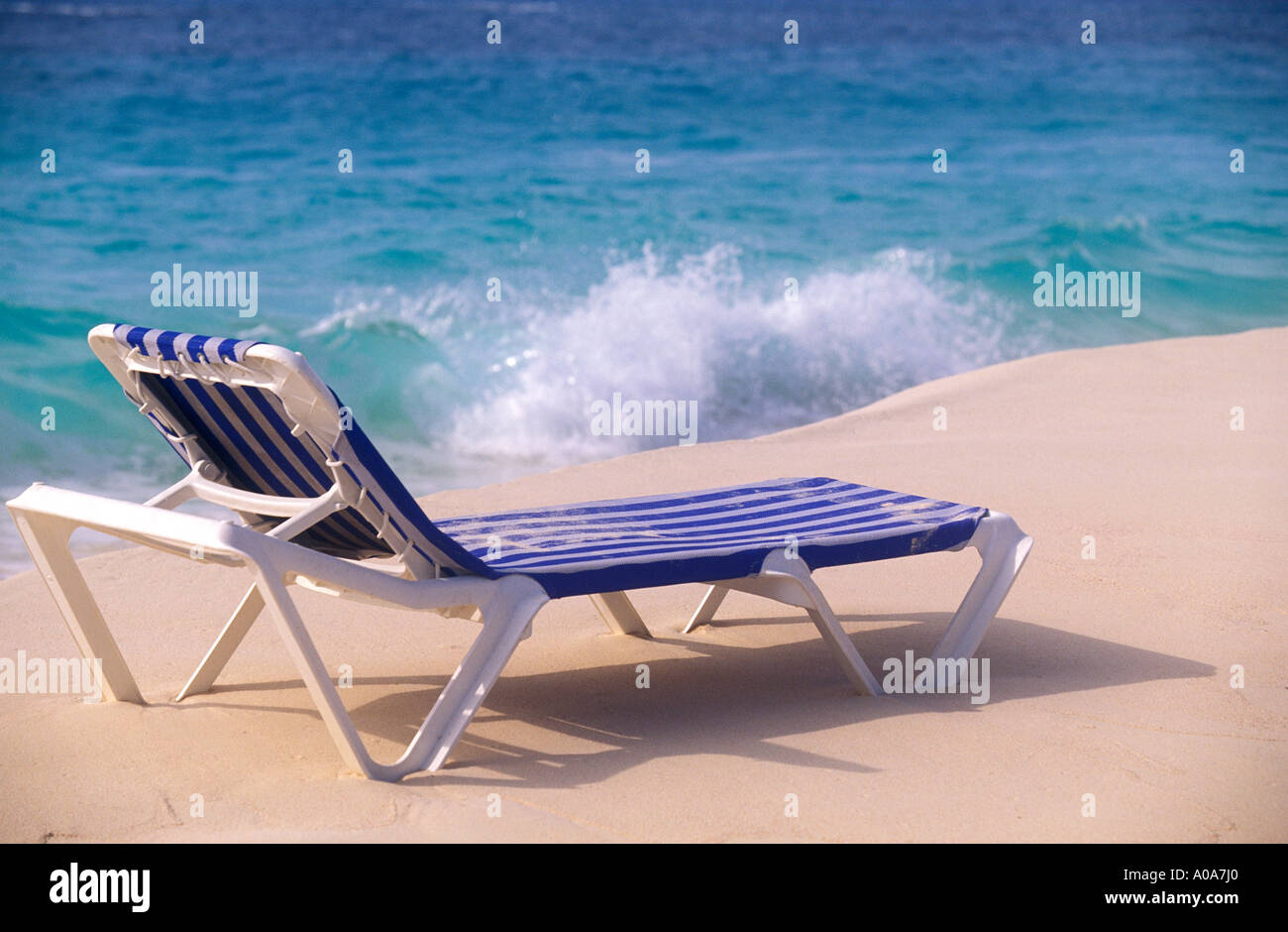 CARIBBEAN Blue beach chair on sandy beach with ocean waves in the ...