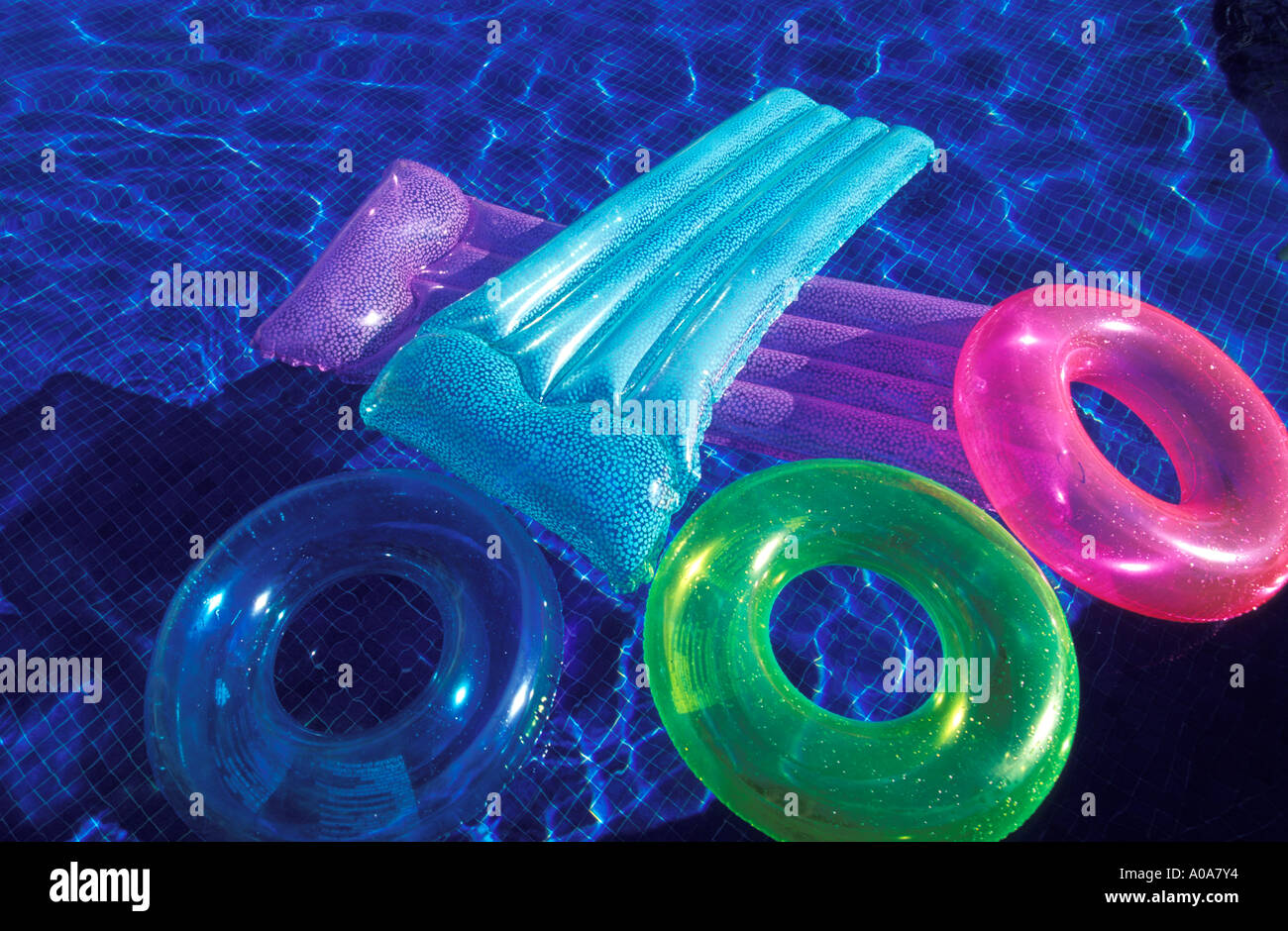 Colorful flotations reflecting against the blue water of a swimming pool Stock Photo