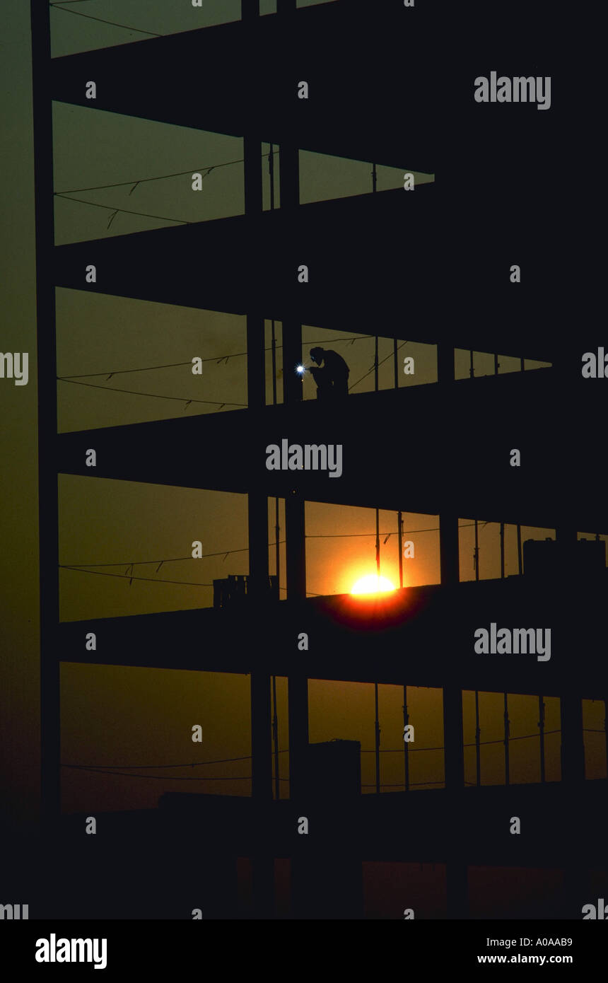 Construction worker does welding on a high rise building at sunrise Stock Photo