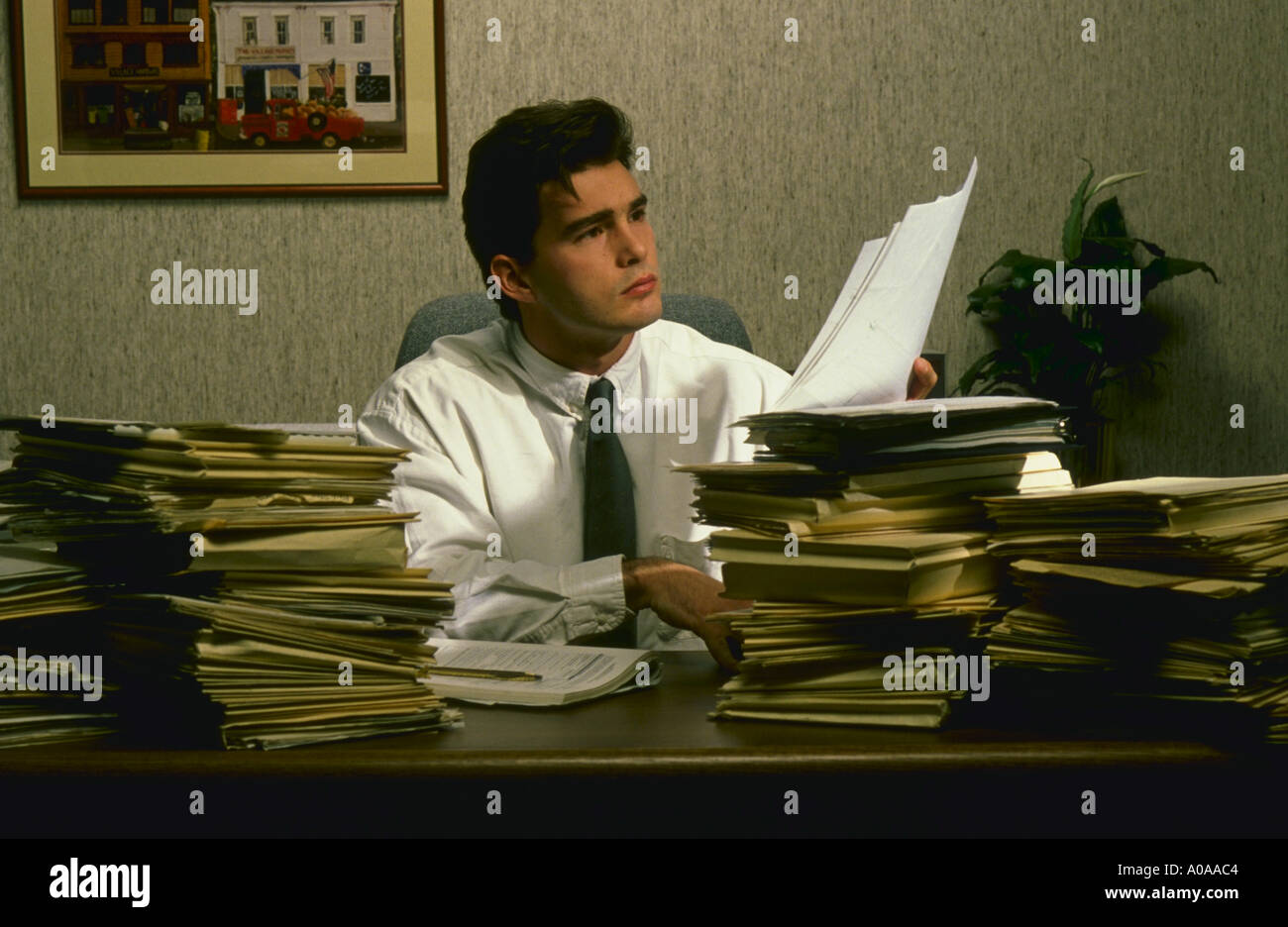 Man wades through paperwork in office Stock Photo