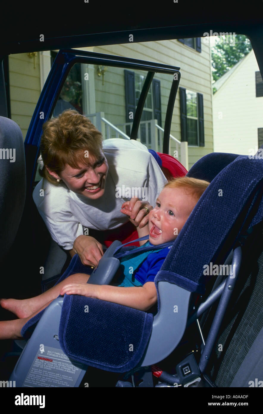 Meg Bowel strapping son into baby car seat Stock Photo Alamy