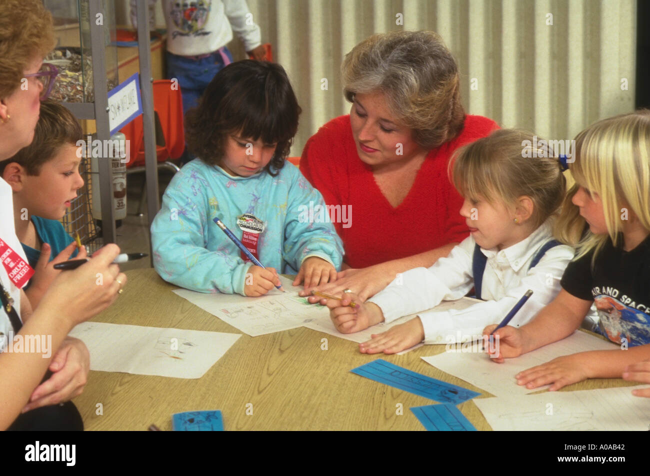Teacher and aid work with kindergarten children writing their names model released Stock Photo