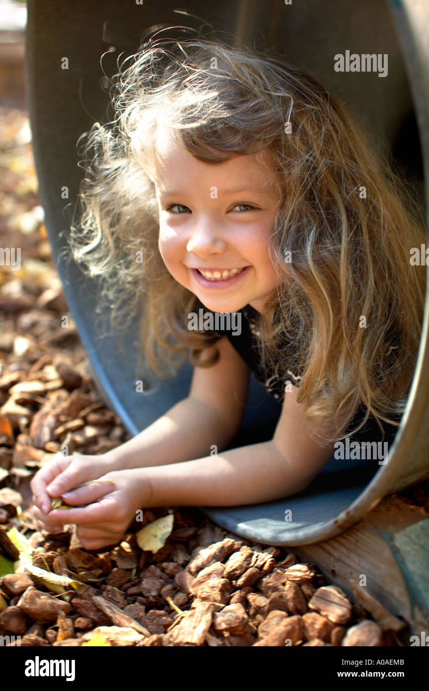 A cute little girl in a playground barrel. Stock Photo
