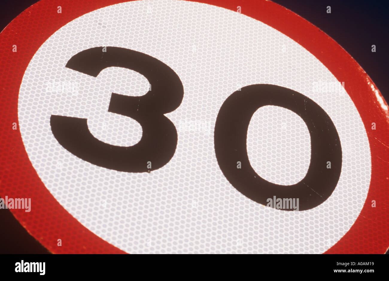 Close up of circular speed limit road sign stating 30 against very deep blue sky Stock Photo