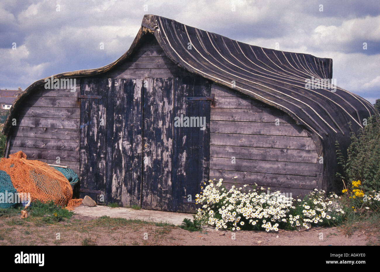 Unusual storage shed made from an upturned boat on Holy Island Northumberland England Stock Photo