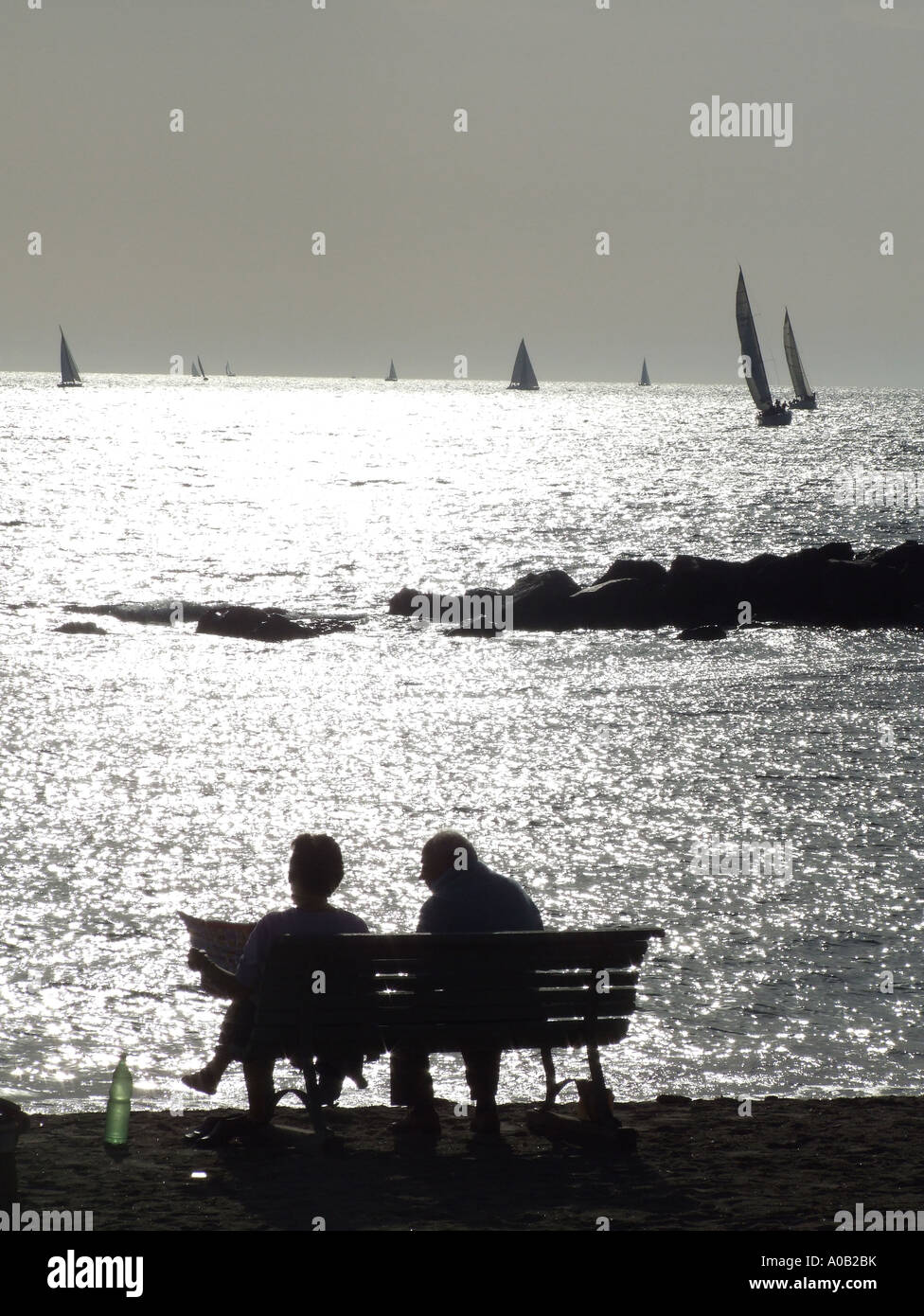 old elderly couple sitting on bench by beach Stock Photo - Alamy