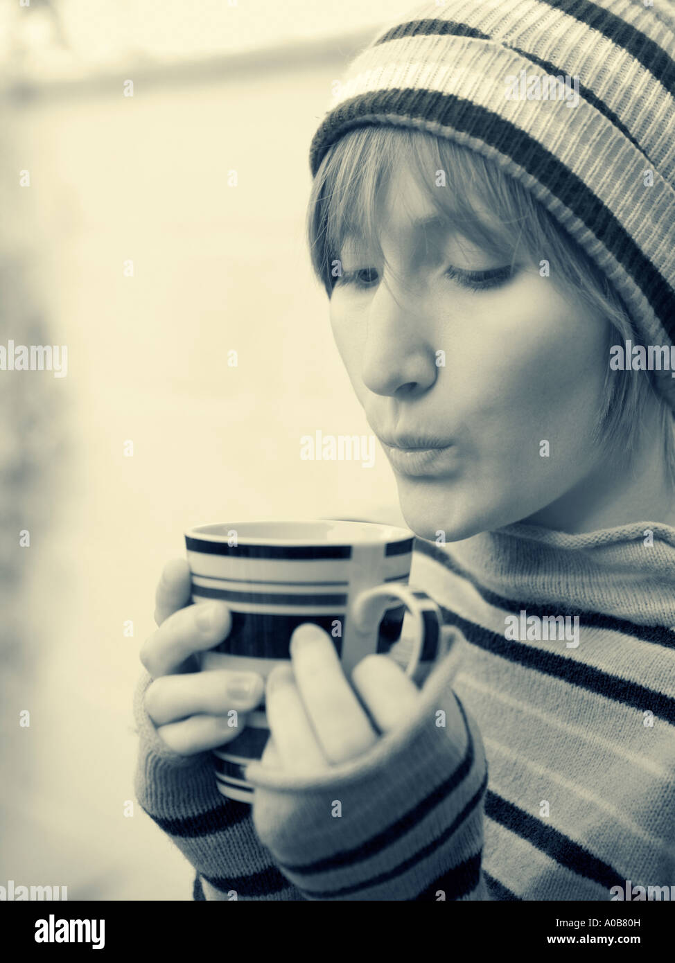 Young woman outdoors blowing on hot drink Stock Photo
