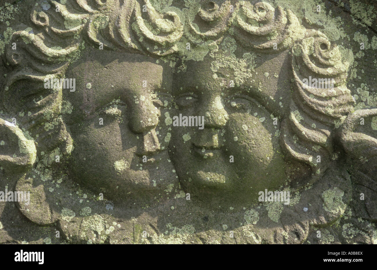 Detail of lichen-covered gravestone dated 1833 with two close heads of cherubic angels carved in naive style Stock Photo