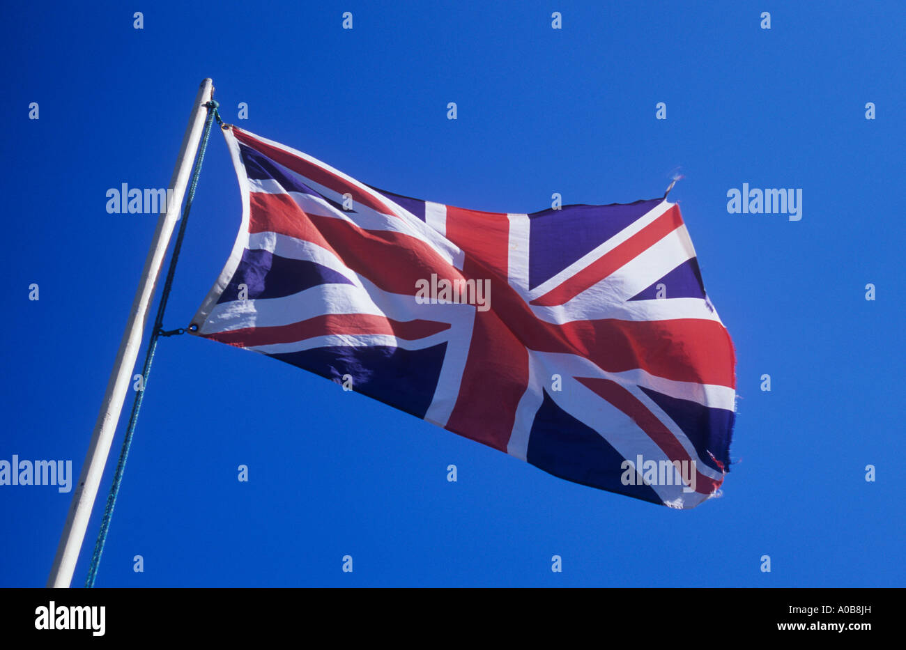 Union Jack flag fluttering from flagpole against clear blue sky Stock Photo