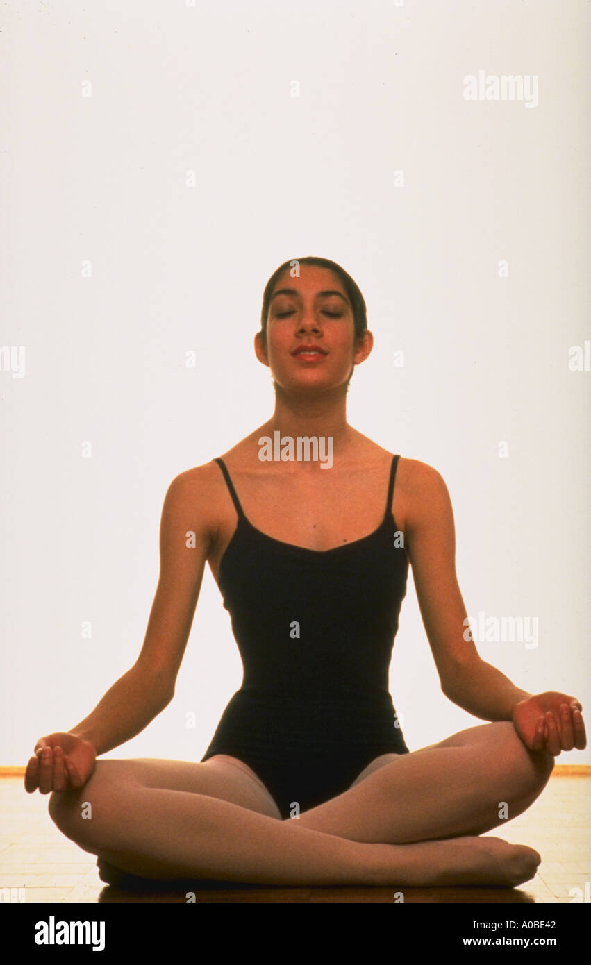 Woman in a leotard sitting in yoga position and peacefully meditating Stock Photo