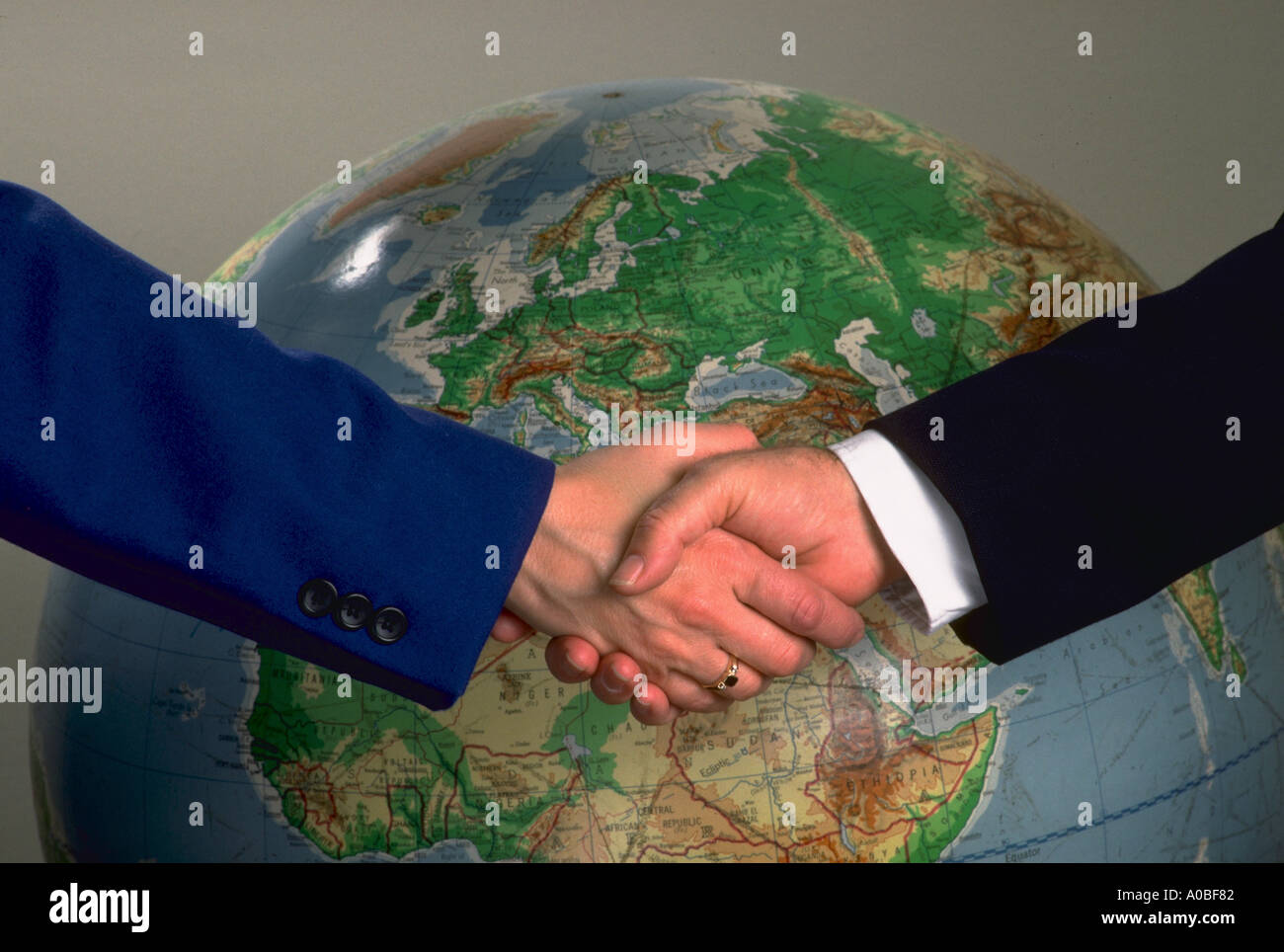 Man and woman shake hands in front of globe Stock Photo