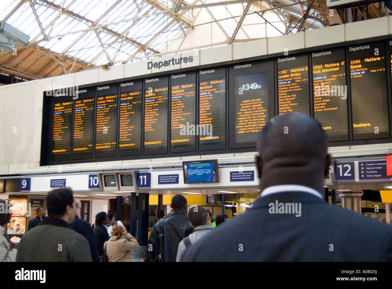 Rail passengers looking at departures board of Victoria station Stock