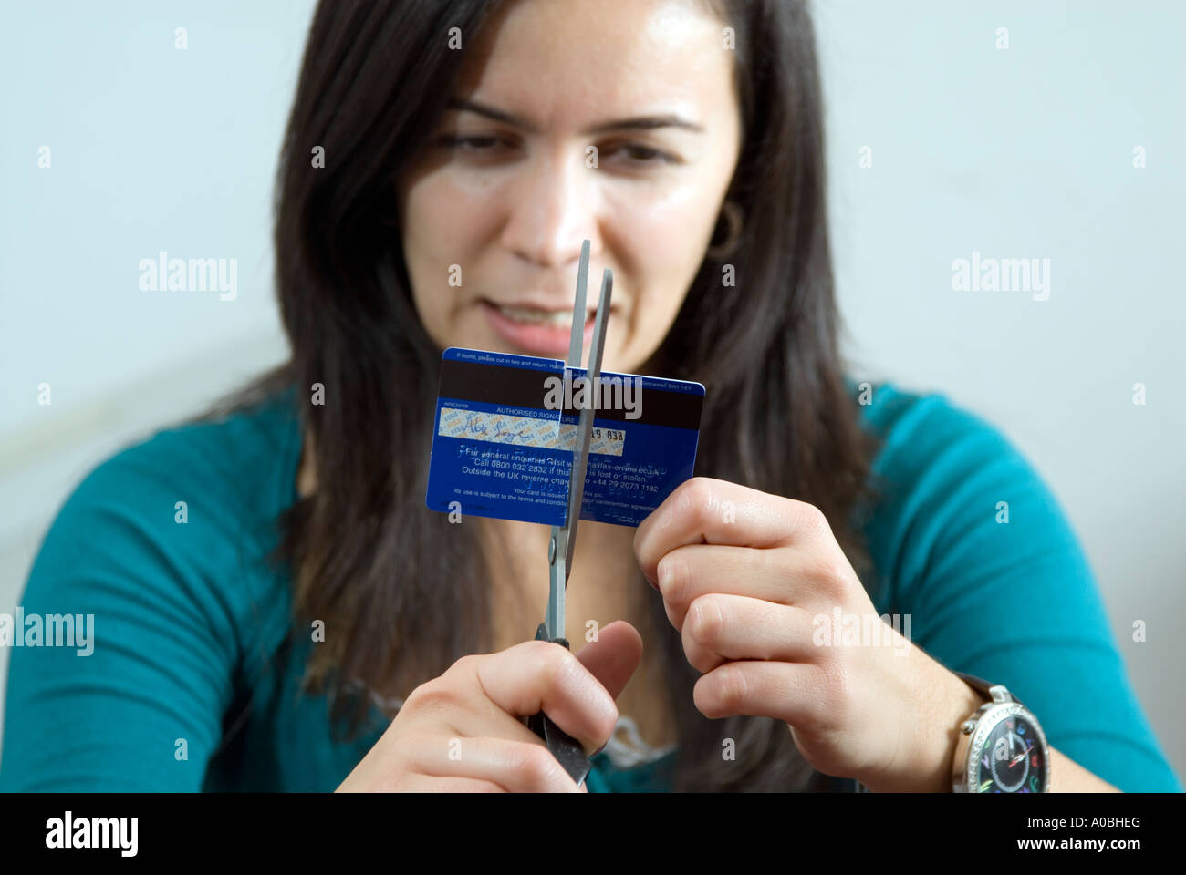 Young woman cutting up credit card with scissors, England UK Stock Photo