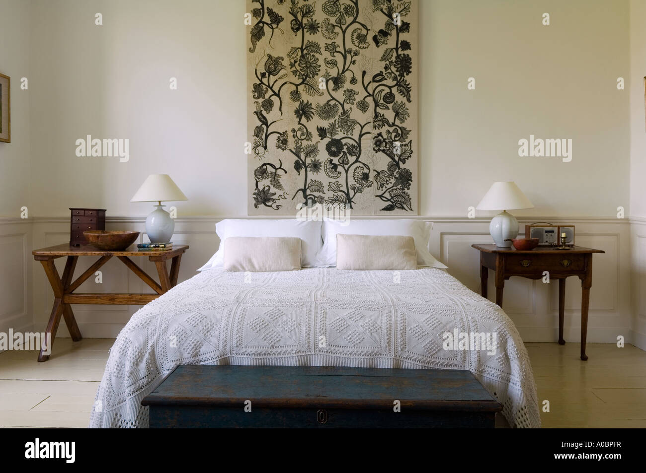 Floral patterned wall hanging above double bed with side tables Stock Photo