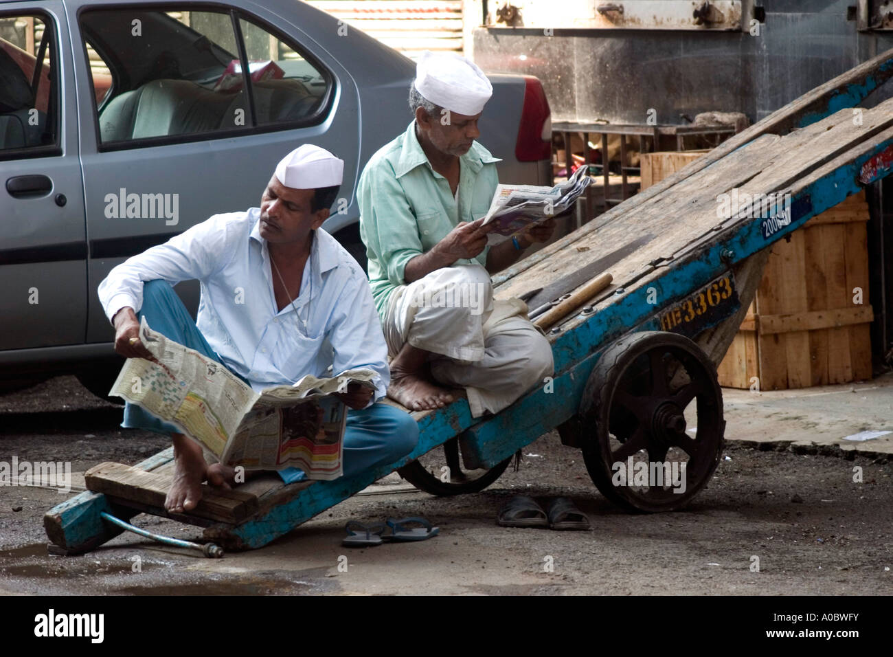 Hand-cart pullers catch up on the morning news on an early moring in Bombay or Mumbai India Stock Photo