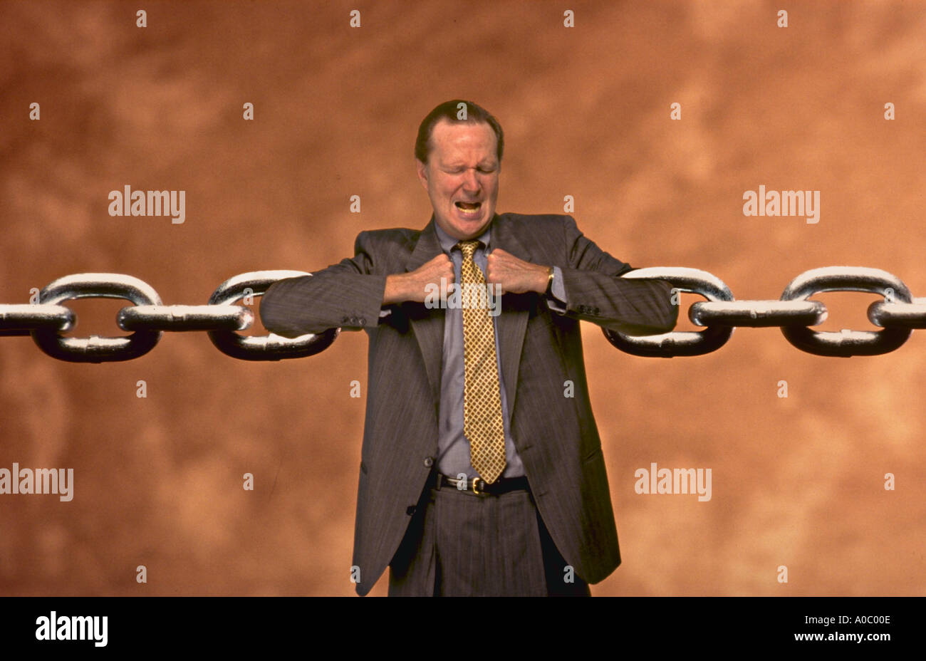 Businessman straining to hold to ends of chain Stock Photo