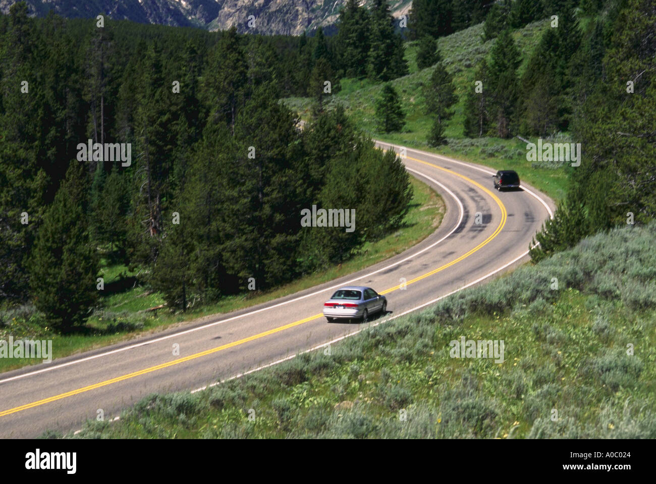 Cars on highway curving into the Grand Teton Mountains Stock Photo