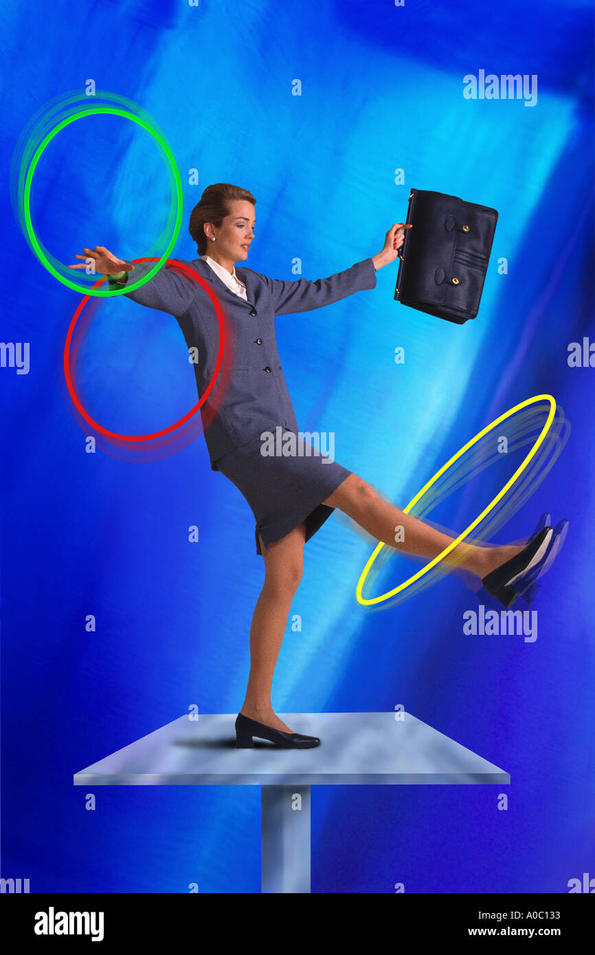 Businesswoman twirling hula hoops depicting concept of trying to handle multiple tasks all at once Stock Photo