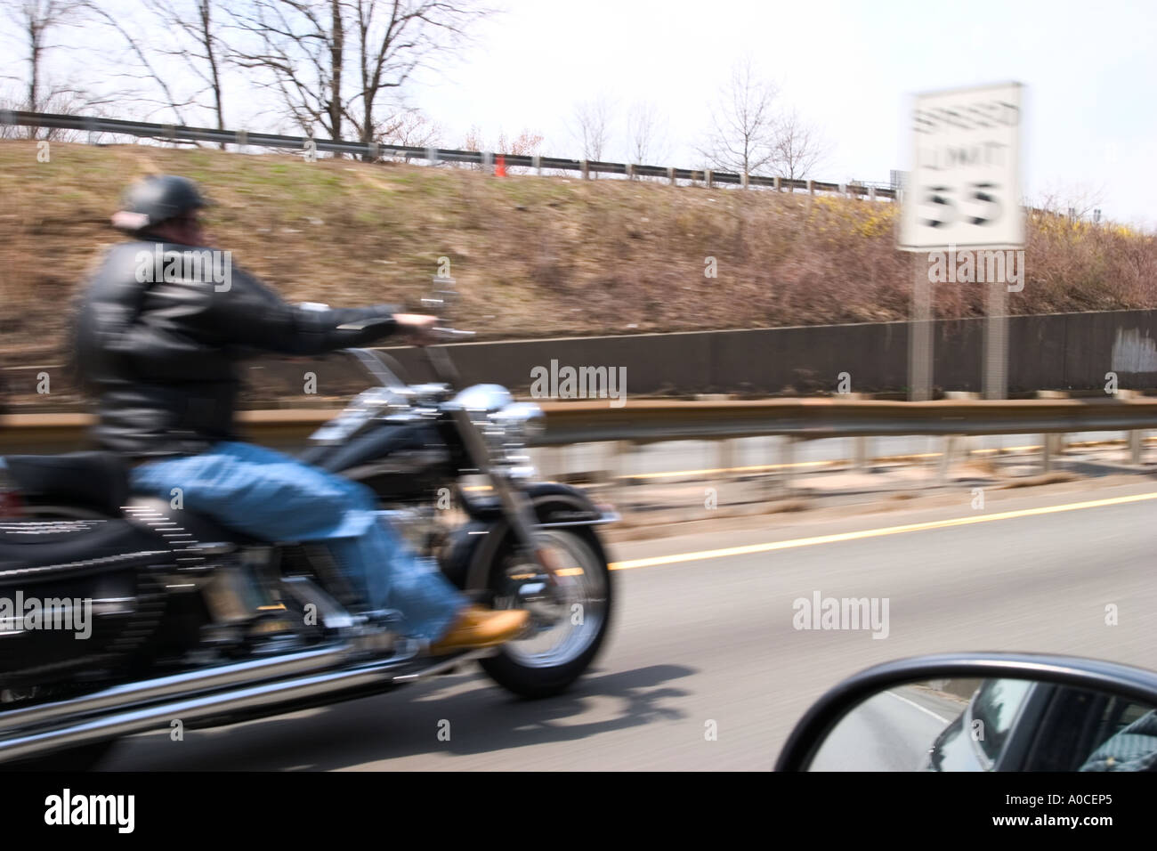 Motorcycle speeding down the highway approaching a speed limit sign Stock Photo