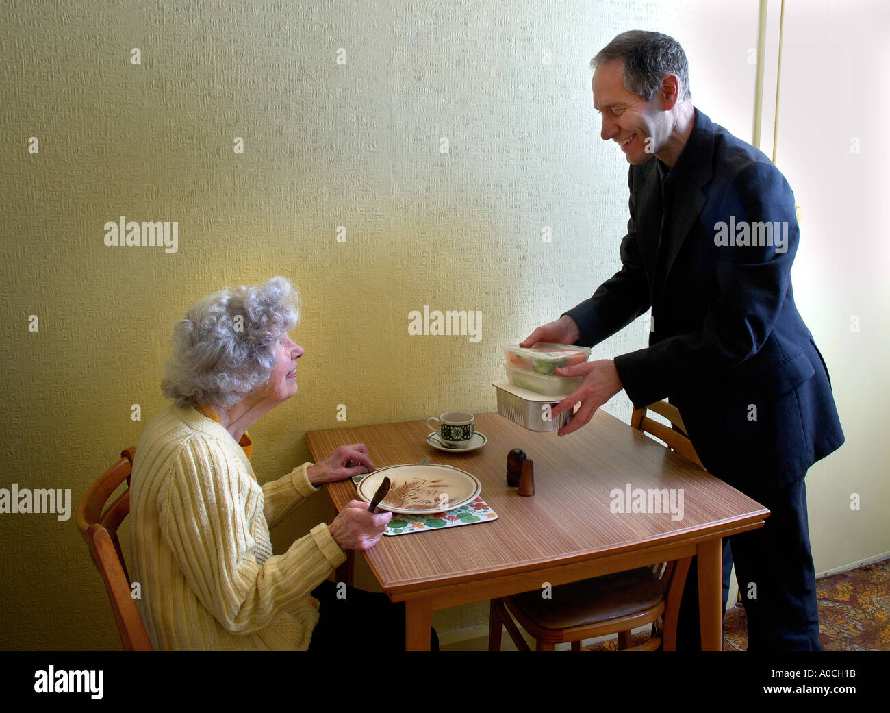 man giving elderly woman prepackaged meal Meals on wheels service Stock Photo
