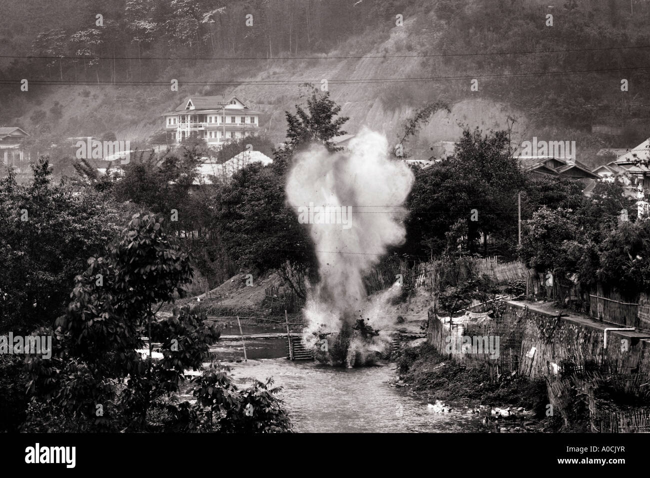 A controlled explosion carried out by UXO Lao on a cluster bomb unit in a river in Sam Neua, Laos Stock Photo