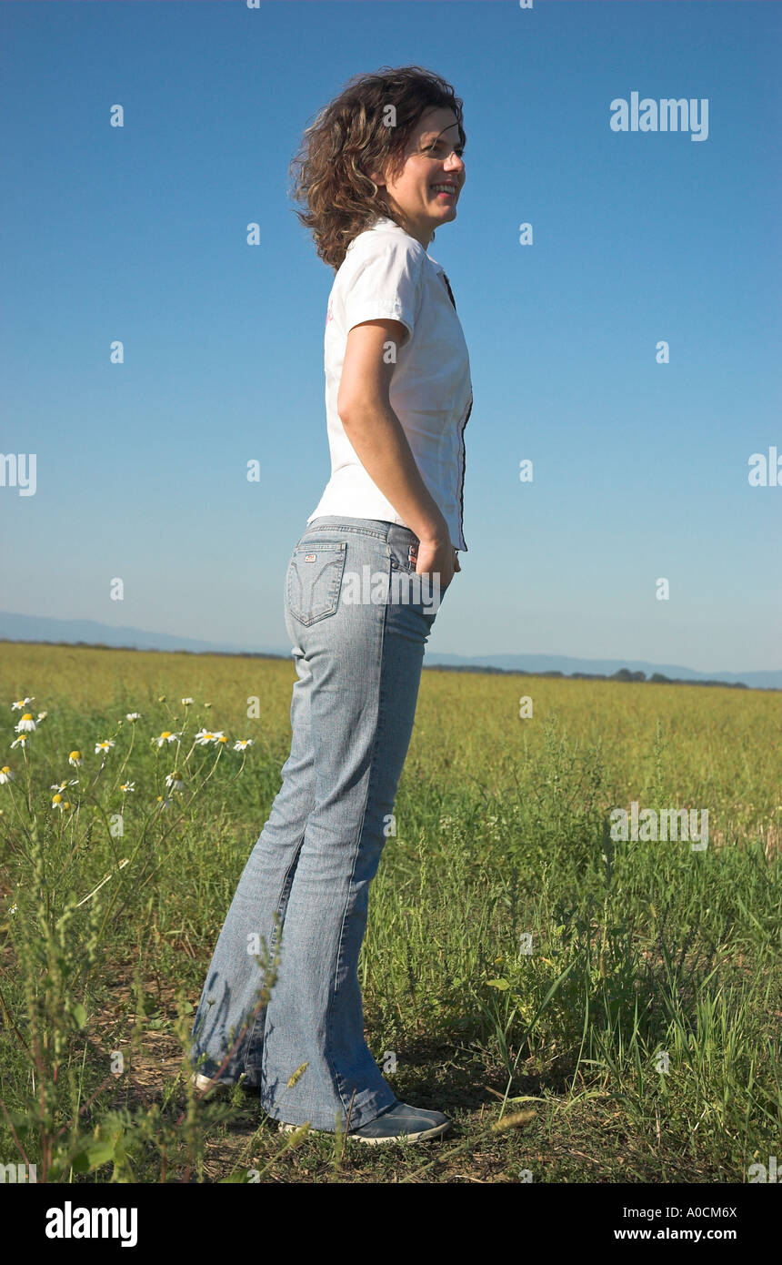 Smiling young woman standing in field looking away Stock Photo