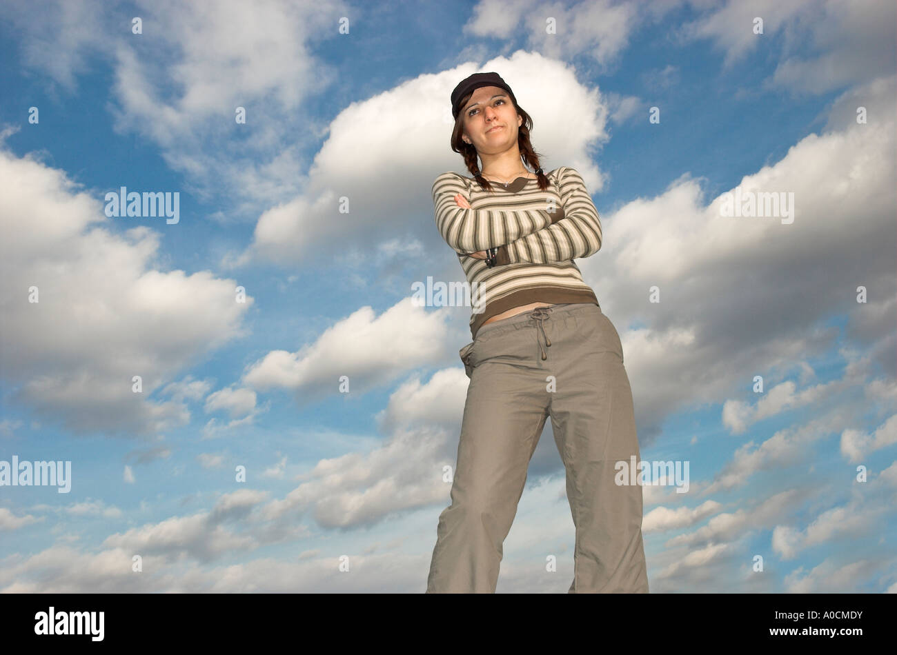 Young woman with plaits wearing cap standing outdoors arms crossed portrait Stock Photo