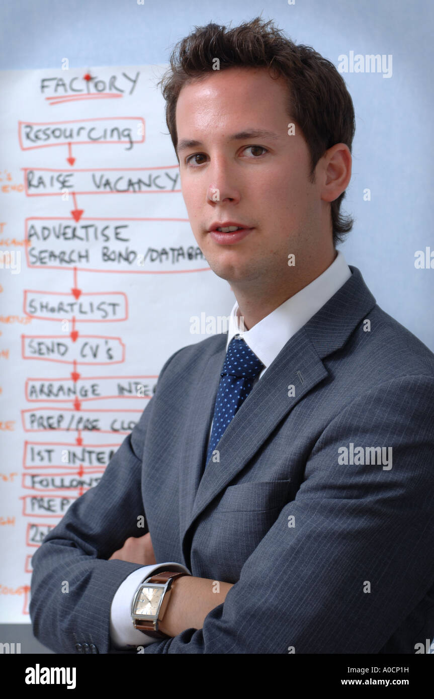 PORTRAIT OF A YOUNG BUSINESSMAN WITH A RECRUITING AGENCY FLOW CHART UK Stock Photo