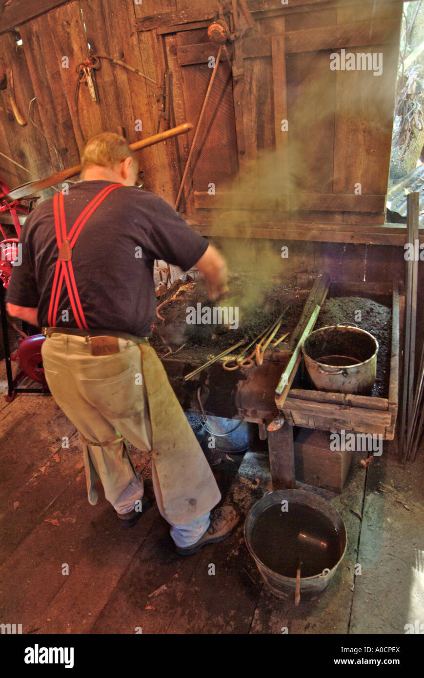 A blacksmith prepares the coal fed fire before working on a metal tool at a saw mill in Occidental California Stock Photo