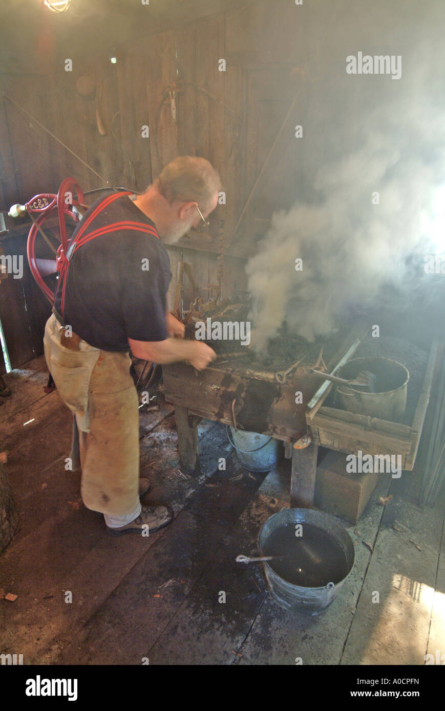 A blacksmith begins heating a piece of metal in the coal fed fire to make a custom tool at a saw mill in Occidental California Stock Photo