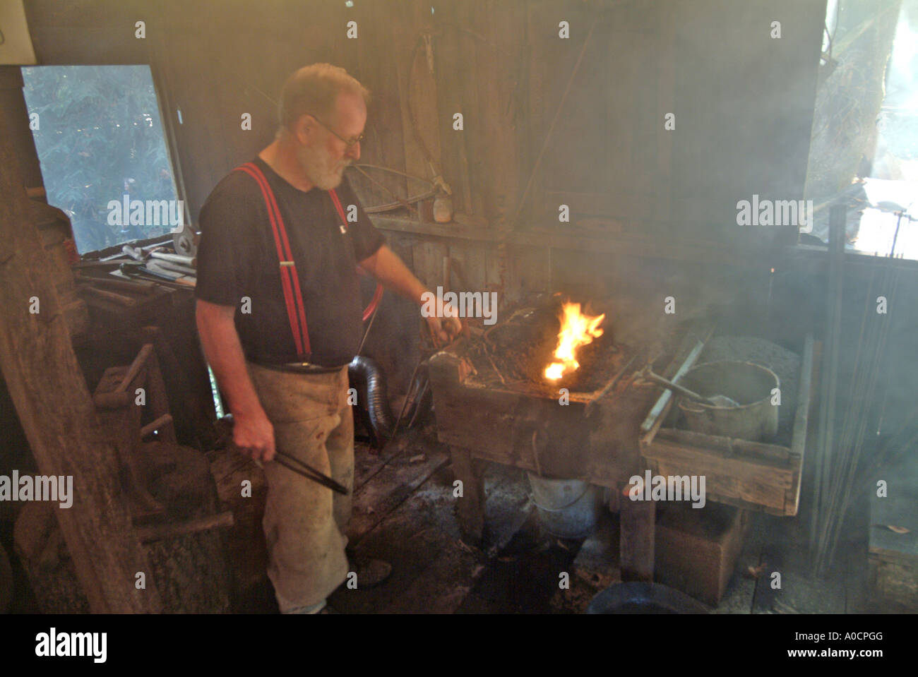 A blacksmith begins heating a piece of metal in the coal fed fire to make a custom tool at a saw mill in Occidental California Stock Photo