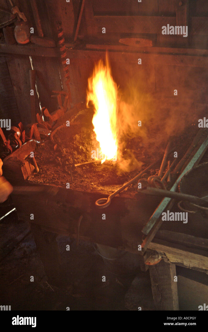 Closeup of fire as a blacksmith pumps more air into the coal fed fire to make it burn hotter as he heats metal to make a tool Stock Photo