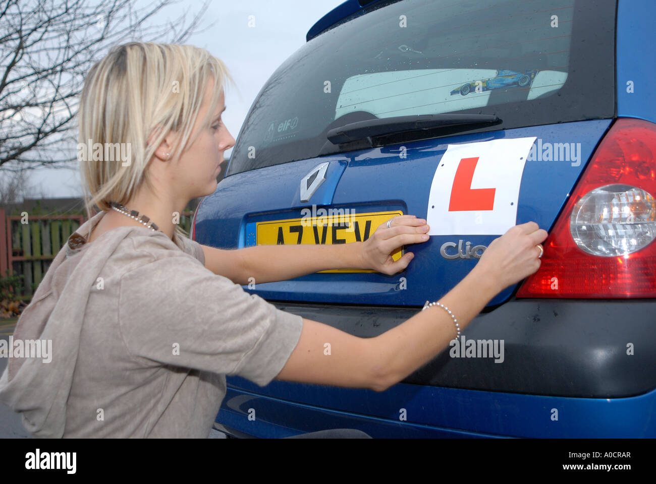 Girl fixing L plate to her car Stock Photo